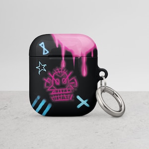 May include: Black Airpods case with a pink, blue, and white graffiti design. The case has a silver ring attached to it for a keychain.
