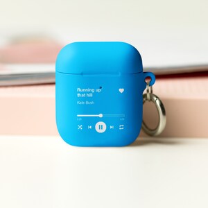May include: A bright blue silicone case for wireless earbuds with a keychain. The case has a white graphic of a music player with the song "Running up that hill" by Kate Bush playing.