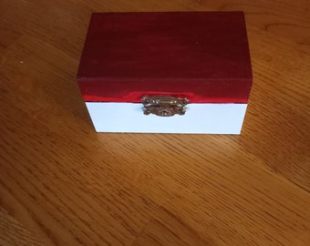 May include: A small wooden box with a red top and a white bottom. The box has a brass latch.