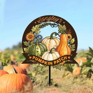 May include: A decorative sign for a pumpkin patch, featuring a circular brown frame with the text "Langley's Pumpkin Patch." The sign displays illustrations of pumpkins, sunflowers, and leaves, set against a field of pumpkins.