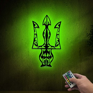 May include: A black and green trident-shaped light with a remote control. The light is on and glowing green.