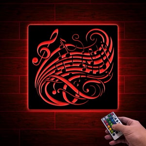 May include: A black light-up wall decor with a red musical note design. The design features a treble clef and musical notes on a swirling background. The light-up decor is controlled by a remote control.