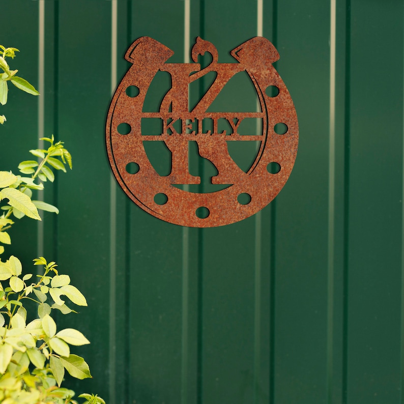 May include: A rusty brown metal horseshoe with the letter K in the center and the name Kelly written inside the horseshoe.
