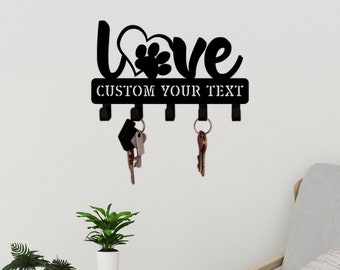 May include: Black metal key holder with the word "Love" in a heart shape with a paw print inside. The key holder has five hooks and a sign that says "Custom Your Text".