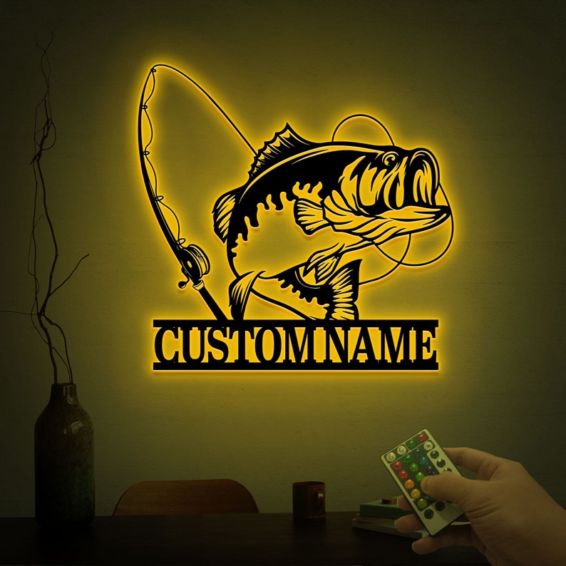 May include: A yellow illuminated wall decor featuring a silhouette of a bass fish with a fishing rod and the text "CUSTOMNAME".