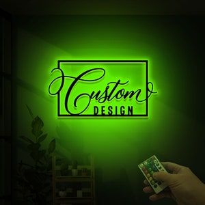 May include: A green neon sign with a black frame and the text "Custom Design" in a cursive font.