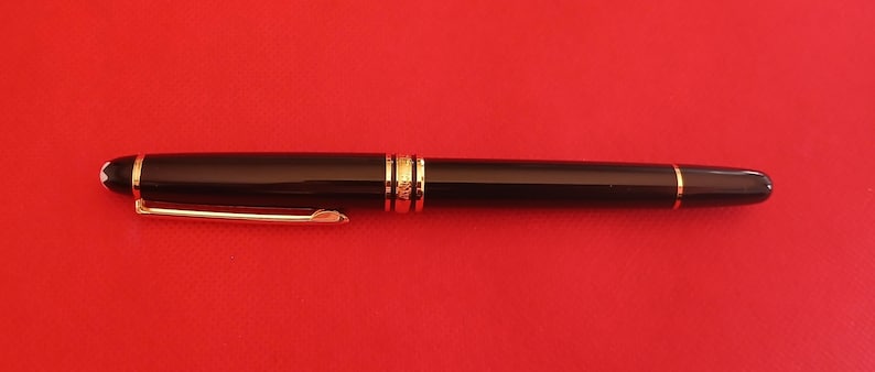 May include: A black and gold fountain pen with a clip on the side.