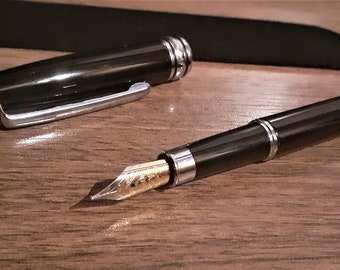 Corps du stylo-plume en métal noir avec détails plaqués argent. Cartouche d'encre noire ou bleue