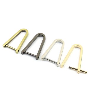 May include: Four metal D-ring clasps in different finishes: gold, gunmetal, silver, and brass. These clasps are ideal for attaching to bags, purses, or other accessories.