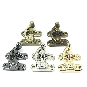 Op de afbeelding: Vijf metalen sluitingen in verschillende afwerkingen: antiek messing, brons, gunmetal, zilver en goud. Elke sluiting heeft een gebogen hendel en een basis met twee schroefgaten. Deze decoratieve sluitingen zijn geschikt voor dozen, kisten of knutselprojecten.