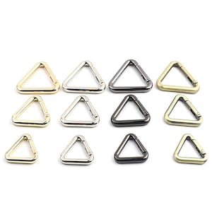 Può includere: Dodici chiusure in metallo a forma triangolare in tre diverse dimensioni e tre diverse finiture: oro, argento e nero.