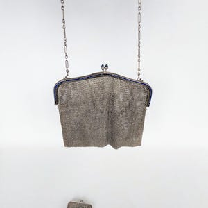 May include: A silver chain bag with a blue trim and a matching smaller bag. The bag is made of a fine mesh material.