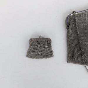 May include: Two silver mesh purses, one small and one large, with a silver chain attached to the larger purse.