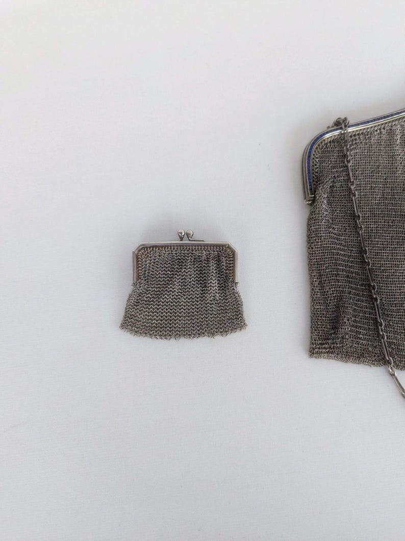 May include: Two silver mesh purses, one small and one large, with a silver chain attached to the larger purse.