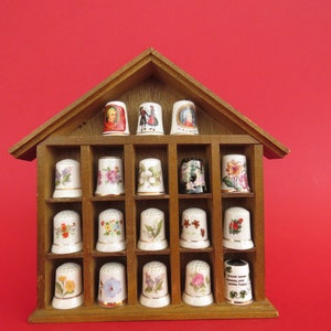 Wooden showcase with 18 porcelain thimbles , flowers decoration