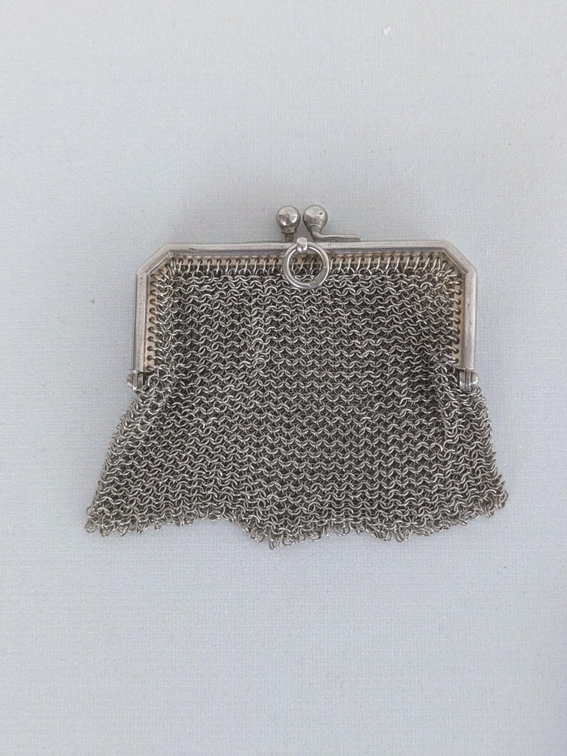 May include: A silver mesh coin purse with a clasp and a ring for a chain.