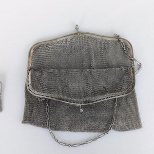 May include: A silver mesh evening bag with a chain strap. The bag is open and the interior is visible.