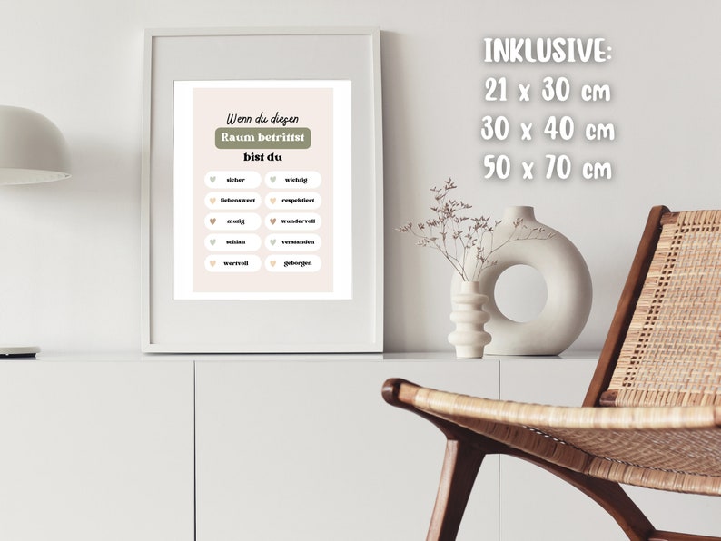 May include: A framed print with a light pink background and green text that reads "Wenn du diegen Raum betrittst bist du". The print has a list of words in white circles with small hearts in front of each word. The words are "wichtig", "bequem", "respektvoll", "mutig", "wunderbar", "muhlos", "vertrauensvoll", "verwirrt", "geborgen". The print is framed in a white frame and is hanging on a white wall. The text "INKLUSIVE: 21 x 30 cm 30 x 40 cm 50 x 70 cm" is written in white on a white background.