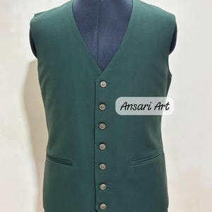 May include: A dark green vest with a V-neck and six buttons down the front. The vest has two front pockets and is displayed on a mannequin. The text "Ansari Art" is visible on the image.