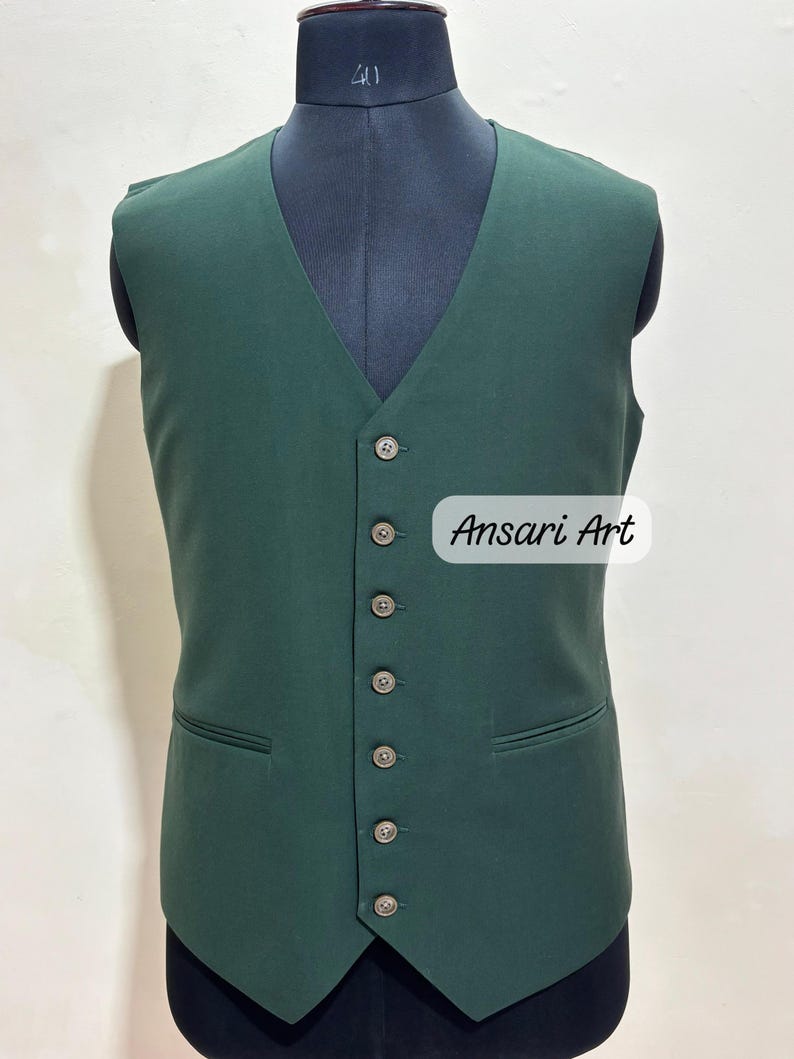 May include: A dark green vest with a V-neck and six buttons down the front. The vest has two front pockets and is displayed on a mannequin. The text "Ansari Art" is visible on the image.