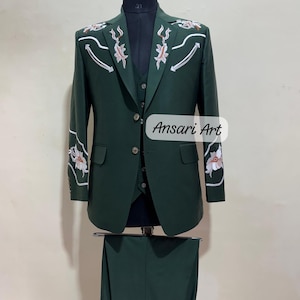 May include: A three-piece dark green suit with floral embroidery on the shoulders and sleeves. The suit includes a jacket, vest, and trousers. The text "Ansari Art" is visible on the lower right side of the image.