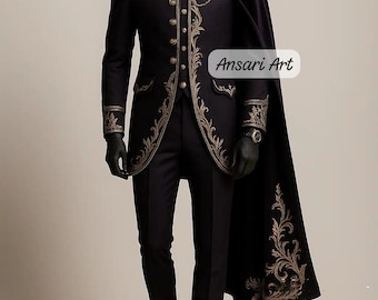 May include: A black formal suit with gold embroidery, featuring a long coat, trousers, and a cape. The suit has ornate gold detailing on the lapels, cuffs, and cape. The text "Ansari Art" is visible on the cape.