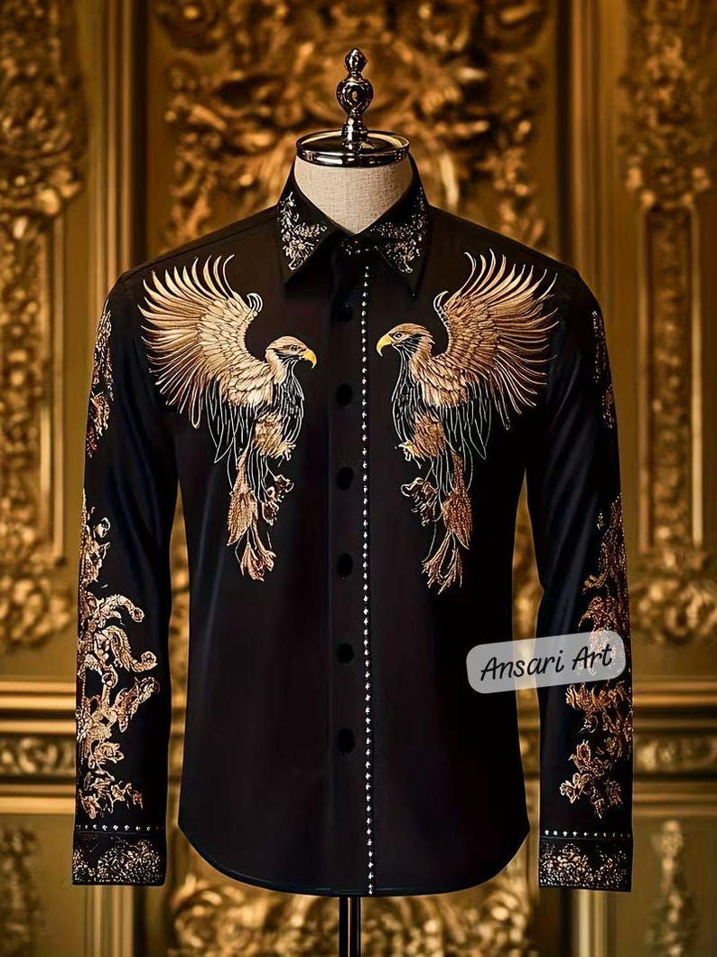 May include: Black button-down shirt with gold embroidered eagle designs on the front and sleeves. The shirt features a detailed collar and cuffs, with a line of small white embellishments down the front. The text "Ansari Art" is visible on the lower right.