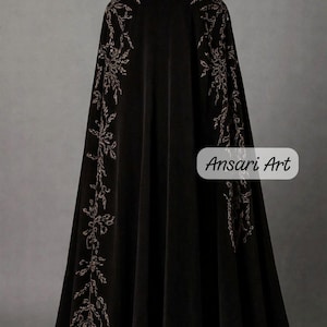 May include: Black velvet cloak with intricate floral embroidery in a contrasting color. The cloak features a high collar and a flowing design, with the text "Ansari Art" on the lower right side.