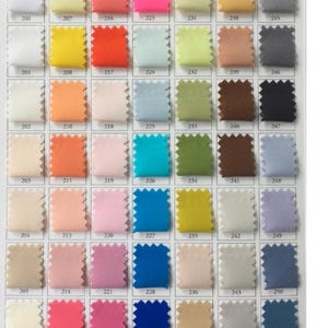 May include: A fabric swatch chart displaying a variety of colors. The chart is organized in rows and columns, with each swatch labeled with a number. Colors range from white and yellow to pink, blue, and green. The edges of each swatch have a zig-zag pattern.
