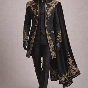 Puede incluir: Un traje formal negro con bordados dorados, que incluye un abrigo largo, un chaleco y un pantalón. El abrigo presenta detalles dorados ornamentados en los hombros, los puños y la parte delantera. Una capa negra con adornos dorados cubre el traje. El maniquí lleva guantes y zapatos negros.
