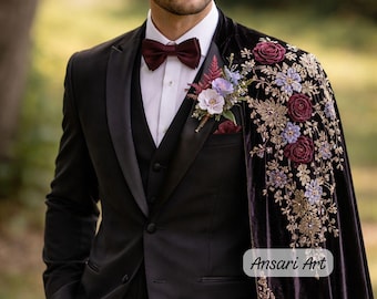 May include: A black tuxedo with a burgundy bow tie and a floral boutonniere. A dark purple velvet cape with gold embroidery and floral accents is draped over the shoulder. The text "Ansari Art" is visible.