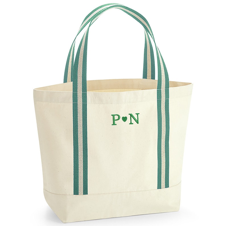 May include: A white canvas tote bag with green striped handles and a green embroidered monogram that says "P&hearts;N".