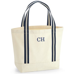 May include: A white canvas tote bag with navy blue stripes and the initials "CH" embroidered on the front.