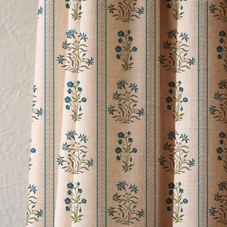 K&ouml;nnte beinhalten: Cremefarbener Stoff mit einem sich wiederholenden Blumenmuster in T&uuml;rkis und Blau. Vertikale t&uuml;rkisfarbene Streifen mit einem blattartigen Design umranden die floralen Motive. Der Stoff hat ein strukturiertes Aussehen, was auf Leinen oder ein &auml;hnliches Material hindeutet.