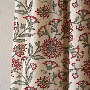 May include: Cream-colored fabric with a repeating floral pattern. The design features red flowers with gray centers and green stems and leaves. The fabric appears to be a curtain or drapery material.