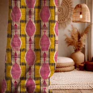 May include: A close-up of a patterned fabric with a repeating design. The pattern features large pink, teardrop-shaped motifs set against a yellow and beige background with black vertical lines. The fabric has a textured appearance.