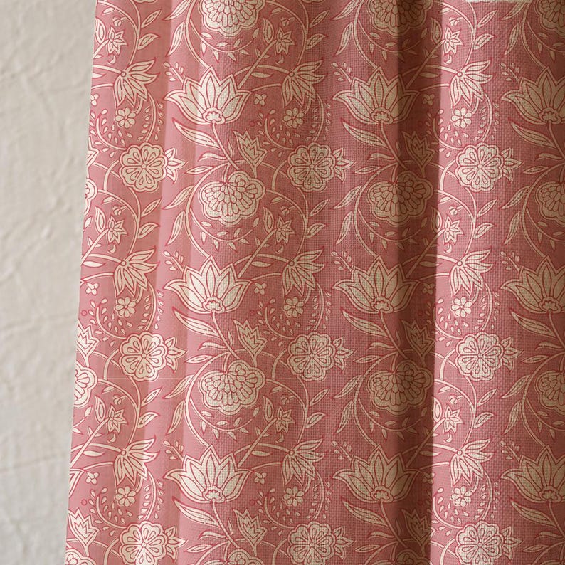 May include: Close-up of a pink floral patterned fabric. The fabric features a repeating design of white flowers and leaves on a pink background. The fabric is likely used for curtains or upholstery.