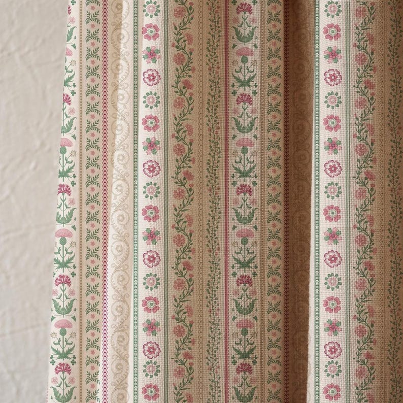 May include: Close-up of a fabric with a repeating vertical pattern. The design features alternating stripes of floral and geometric motifs in shades of pink, green, and beige. The fabric has a vintage, classic aesthetic.