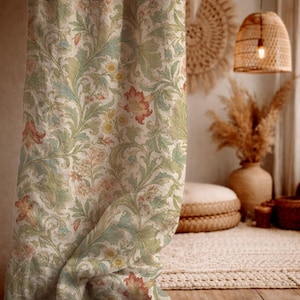 May include: A curtain featuring a repeating botanical pattern with sage green leaves, muted orange trumpet-shaped flowers, and small yellow blossoms on a cream-coloured background. The fabric displays intricate swirling vines and foliage.