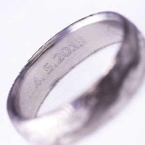 May include: A silver wedding band with the date "4.5.2013" engraved on the inside.