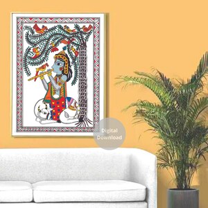 May include: A colorful Madhubani painting depicting a blue-skinned figure playing a flute while sitting on a white cow. The figure is surrounded by a green tree with red and yellow birds. The painting is framed in a gold frame.