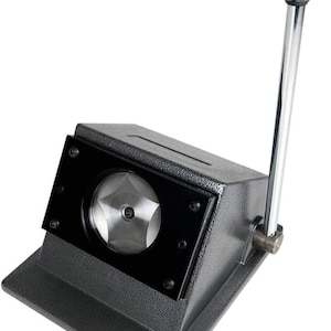 May include: A black metal circle cutter with a silver blade and a black handle. The cutter is used to cut circles out of paper, cardstock, and other materials.