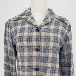 May include: A vintage plaid jacket in beige, blue, and red. The jacket features a collared neckline, long sleeves, and a button-down front. It has two front pockets and is displayed on a mannequin.