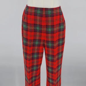 May include: Red plaid pants with a straight leg design. The pants feature a classic tartan pattern in red, green, blue, and yellow. The garment is displayed on a mannequin.