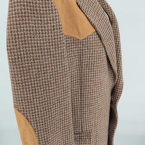 Peut inclure: Un blazer en tweed marron et beige avec des coudi&egrave;res et des empi&egrave;cements d'&eacute;paule en daim. Le blazer pr&eacute;sente un motif pied-de-poule classique et un revers crant&eacute;. Le v&ecirc;tement est pr&eacute;sent&eacute; sur un mannequin.