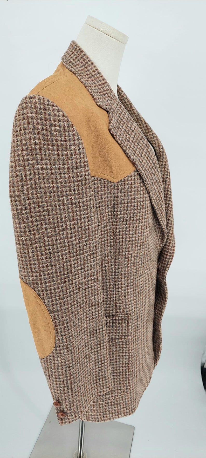 Peut inclure: Un blazer en tweed marron et beige avec des coudi&egrave;res et des empi&egrave;cements d'&eacute;paule en daim. Le blazer pr&eacute;sente un motif pied-de-poule classique et un revers crant&eacute;. Le v&ecirc;tement est pr&eacute;sent&eacute; sur un mannequin.