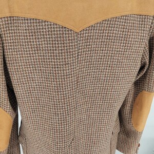 Peut inclure: Veste en tweed marron avec empi&egrave;cements d'&eacute;paules et coudi&egrave;res en daim beige. La veste pr&eacute;sente un motif pied-de-poule classique et une coupe ajust&eacute;e. Une pi&egrave;ce polyvalente pour une garde-robe d'inspiration vintage.