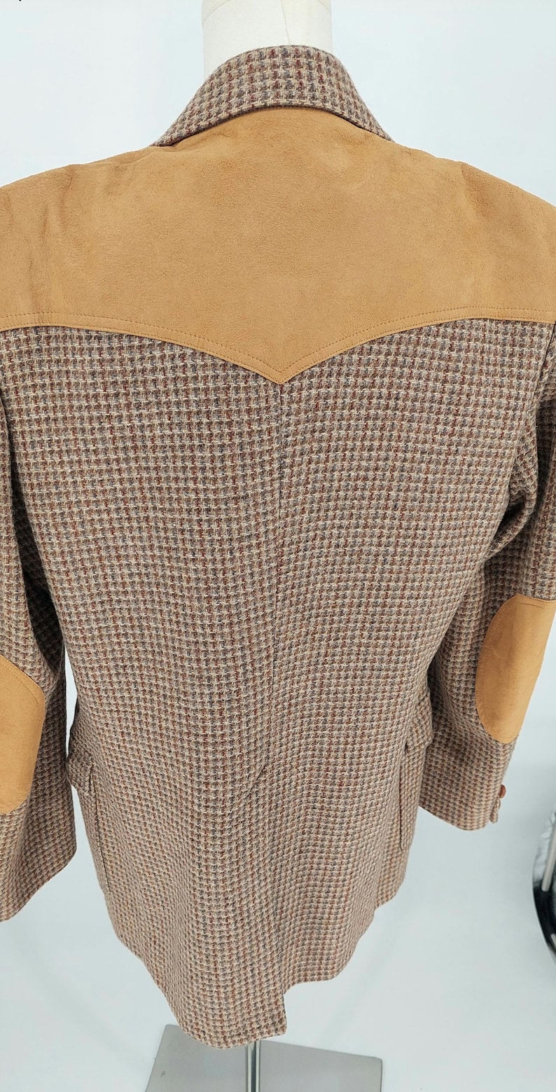 Peut inclure: Veste en tweed marron avec empi&egrave;cements d'&eacute;paules et coudi&egrave;res en daim beige. La veste pr&eacute;sente un motif pied-de-poule classique et une coupe ajust&eacute;e. Une pi&egrave;ce polyvalente pour une garde-robe d'inspiration vintage.