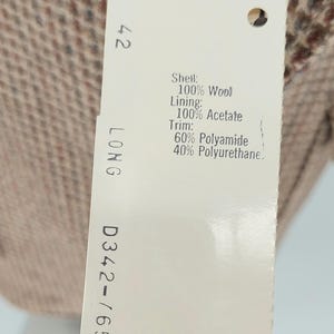 Peut inclure: Une &eacute;tiquette de v&ecirc;tement avec le num&eacute;ro 42 et le mot LONG. L'&eacute;tiquette indique la composition du tissu : 100% laine pour la coque, 100% ac&eacute;tate pour la doublure et garniture de 60% polyamide et 40% polyur&eacute;thane.