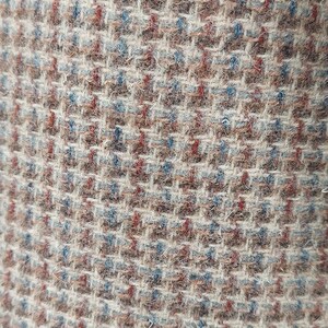Peut inclure: Gros plan sur un tissu textur&eacute; avec un motif tiss&eacute;. Le tissu pr&eacute;sente un m&eacute;lange de couleurs, dont le beige, le marron, le rouge et le bleu, cr&eacute;ant un design subtil mais complexe. Le tissage est serr&eacute; et semble &ecirc;tre un mat&eacute;riau durable.